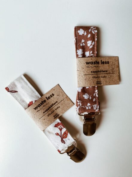 Två napphållare i olika färg med etikett på.